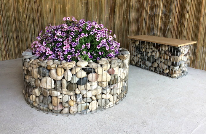 round flowerbed with a border of colored stones in a wire frame