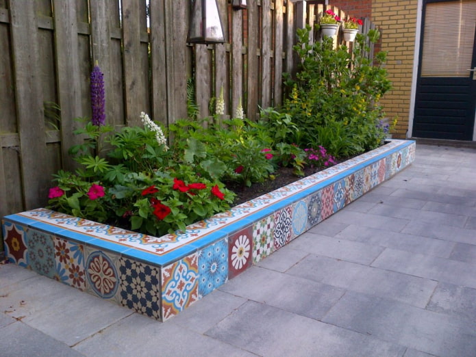rectangular border for a flower bed, lined with colorful tiles