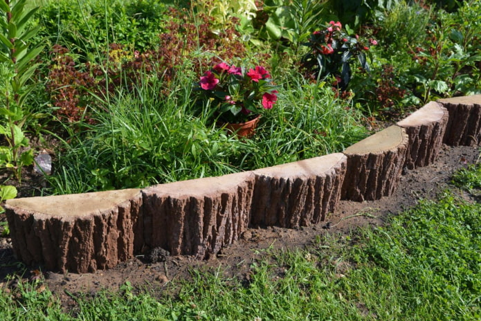 a fence for a flower garden from vertical fragments of logs
