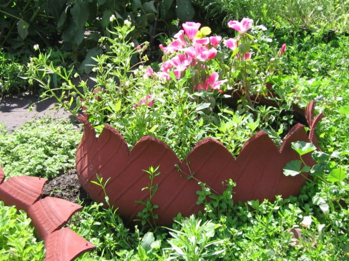 a flowerbed with a curly rim made of a tire painted to resemble a clay pot