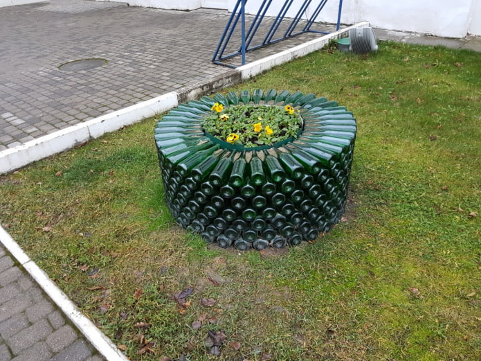 a round flower bed with a border of glass bottles stacked on top of each other